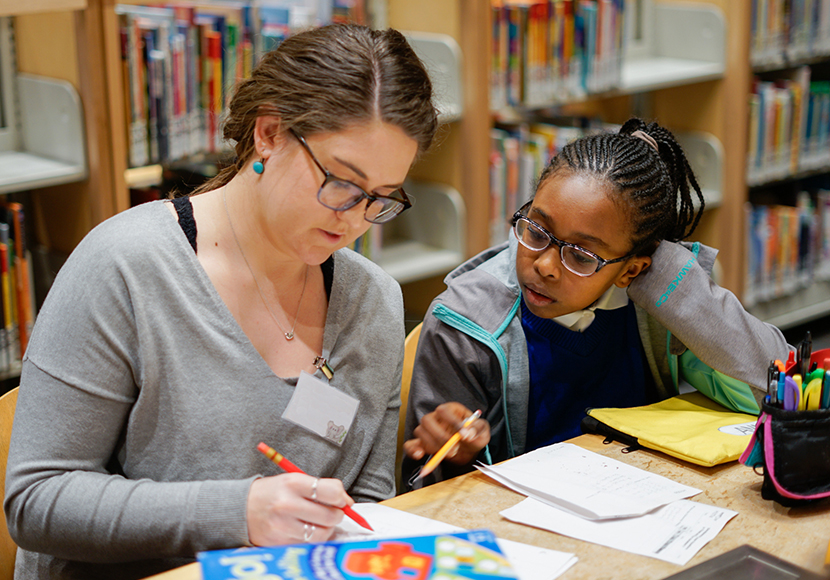 An adult and a child seated at a table reviewing a document.