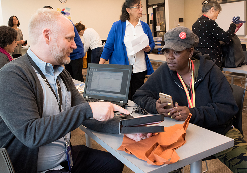 Two adults seated at table with a laptop computer.