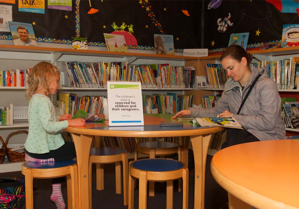 Family reading in children’s area at the NewHolly Branch